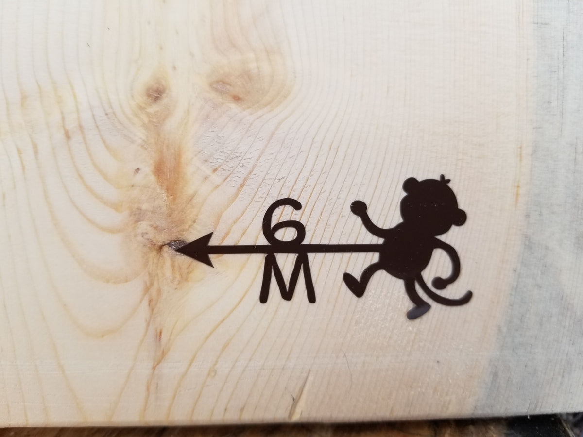 A wooden board with Monkey Height Marking Arrows and Little Prairie Craft Co. on it.