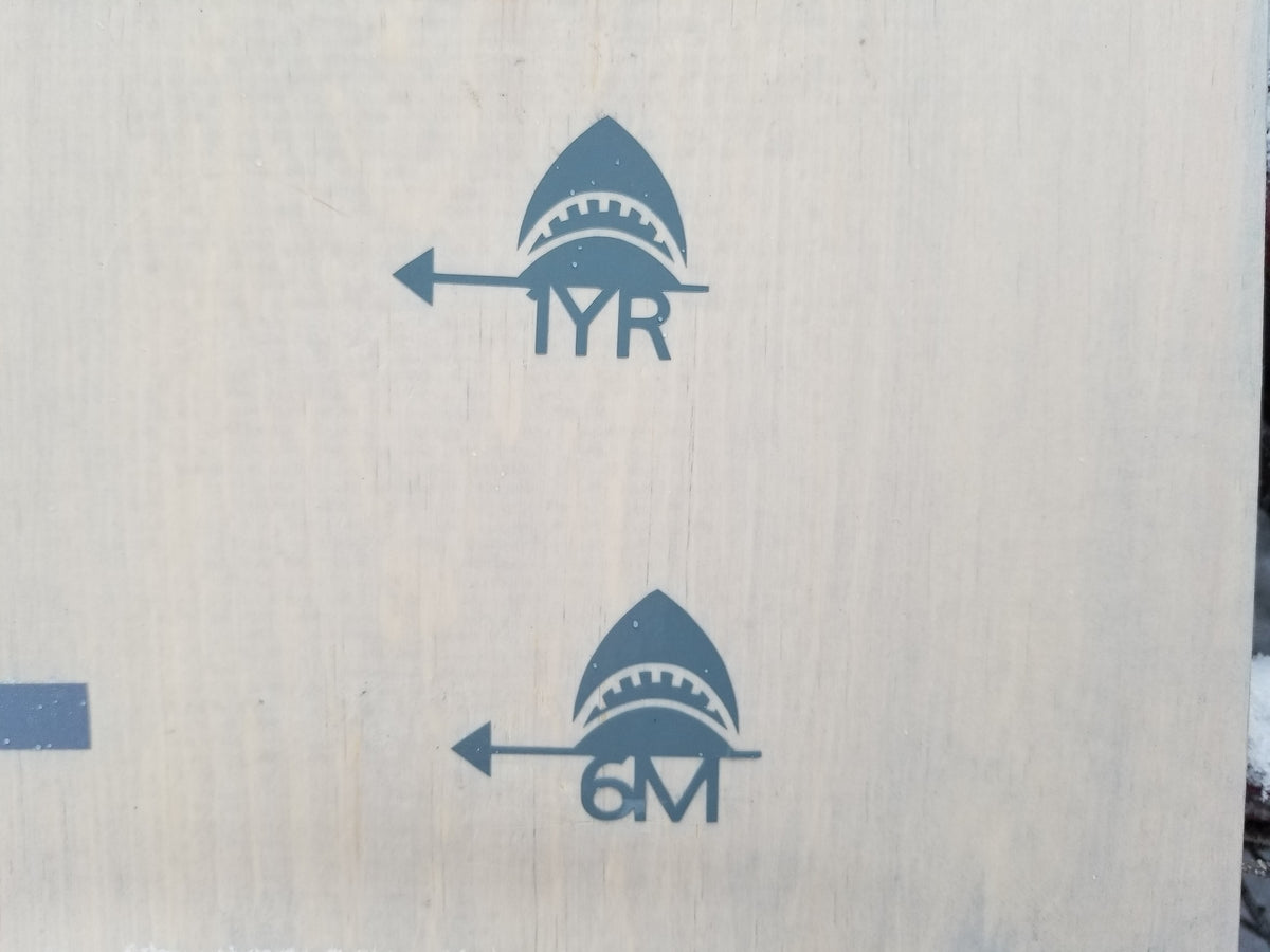 A wooden board with a Shark Height Marking Arrow from Little Prairie Craft Co. on it.