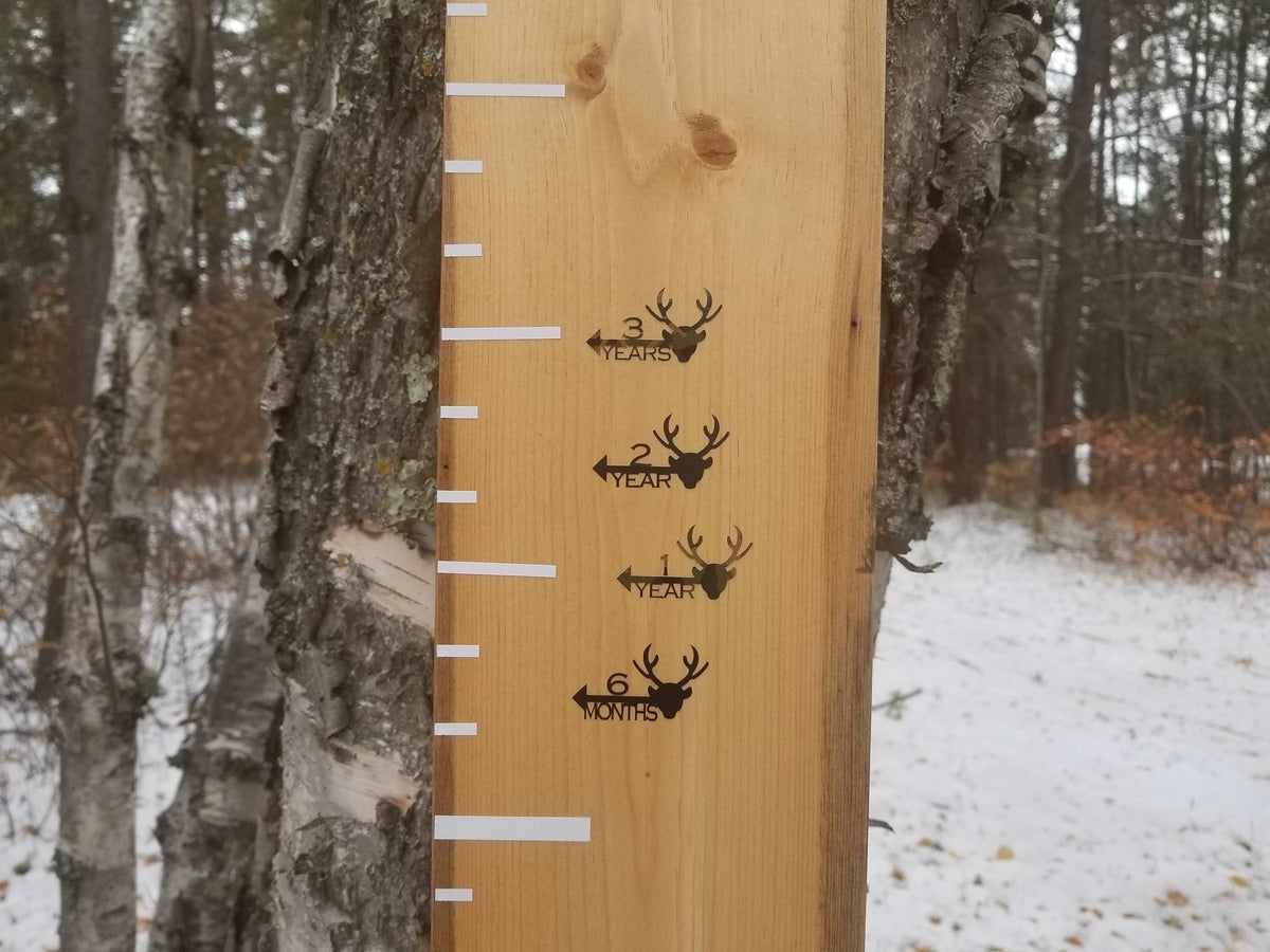 A wooden growth chart with Little Prairie Craft Co. Deer Height Marking Arrows on it.