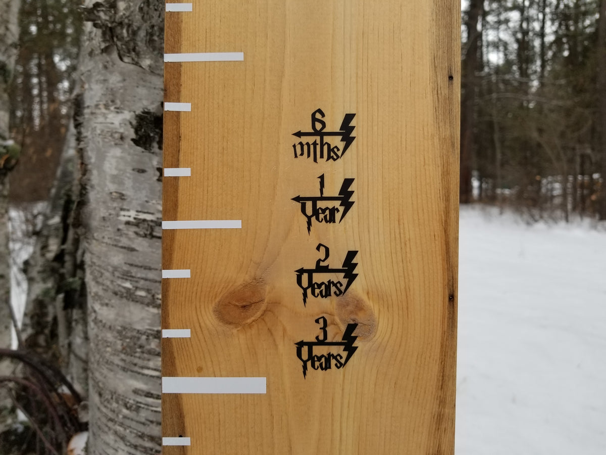 A Little Prairie Craft Co. Lighting Bolt Height Marking Arrows with numbers on it in the woods.