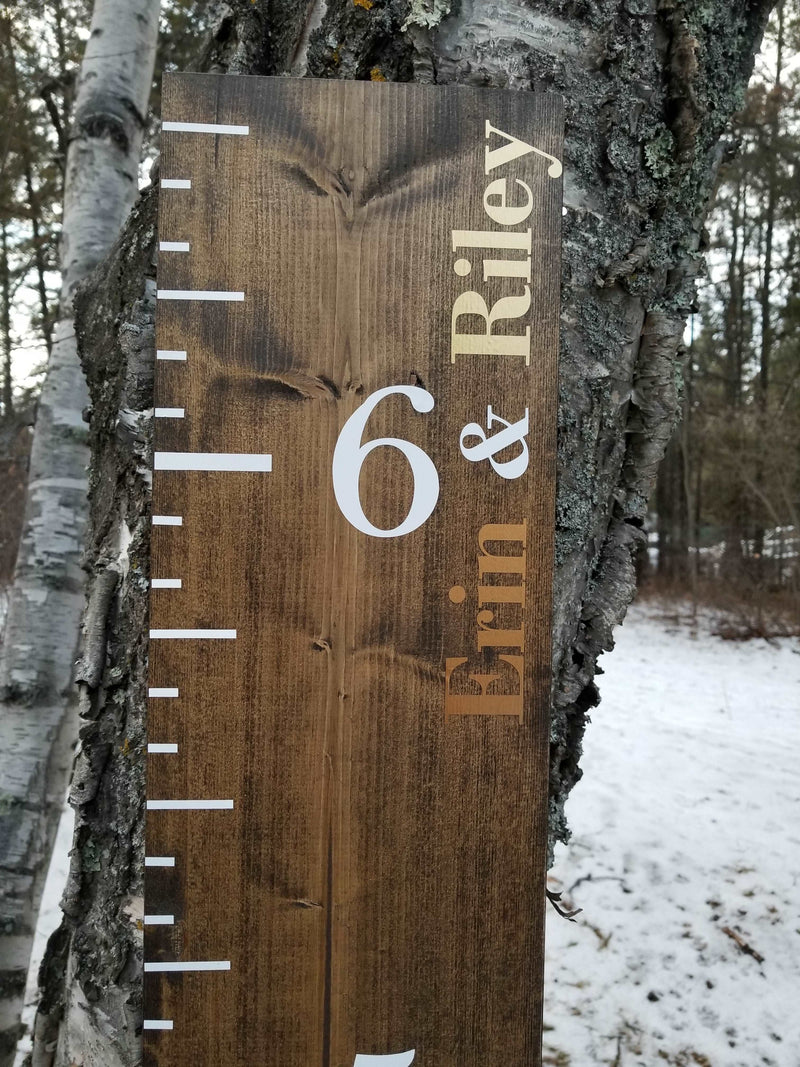 A Little Prairie Craft Co. wooden growth chart with the product name "Add a Name to Growth Chart or DIY Decal" on a tree in the snow.