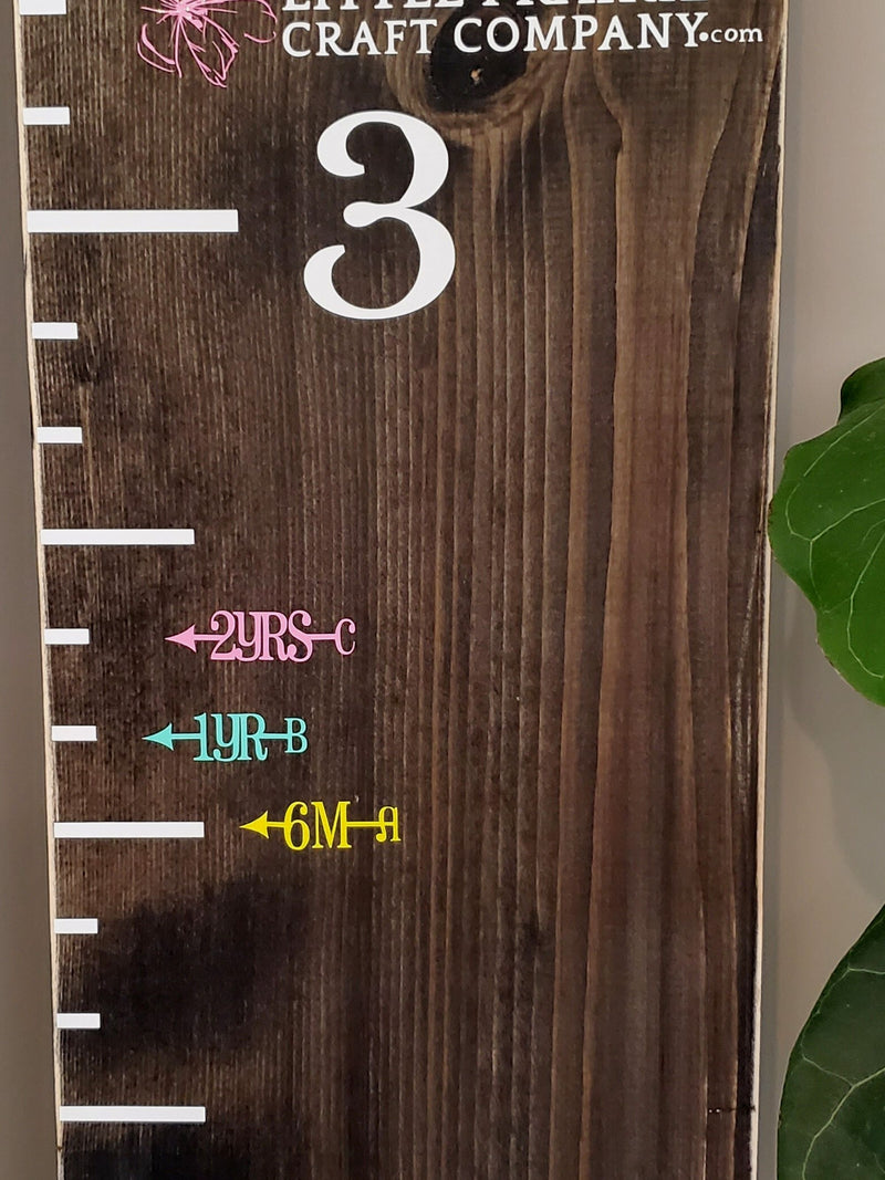 A wooden growth chart with the words Pretty Little Initials Height Marking Arrows by Little Prairie Craft Co.