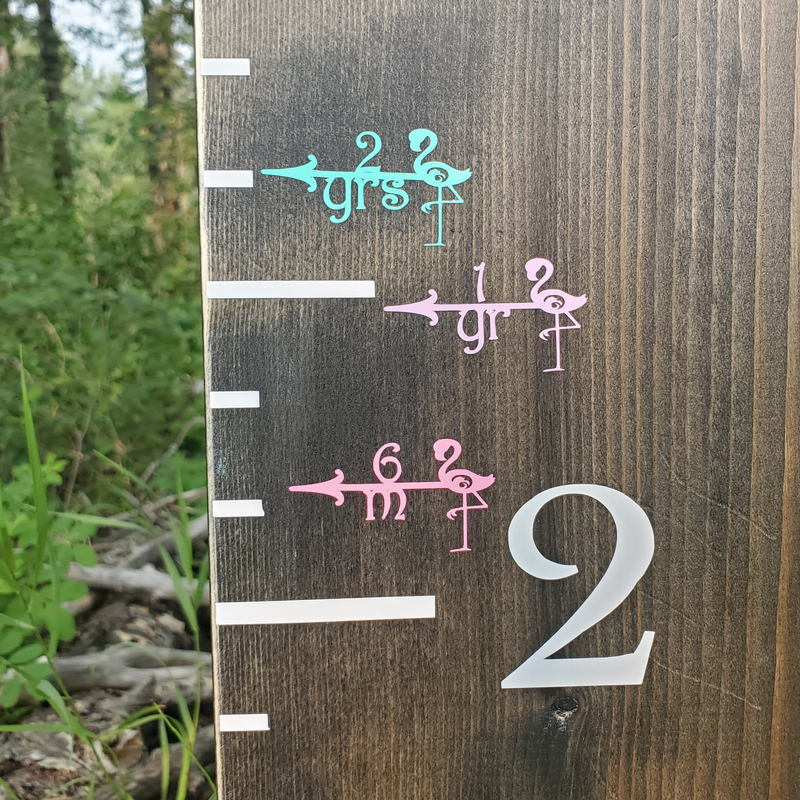 A Little Prairie Craft Co. wooden growth chart with Flamingo Height Marking Arrows on it.