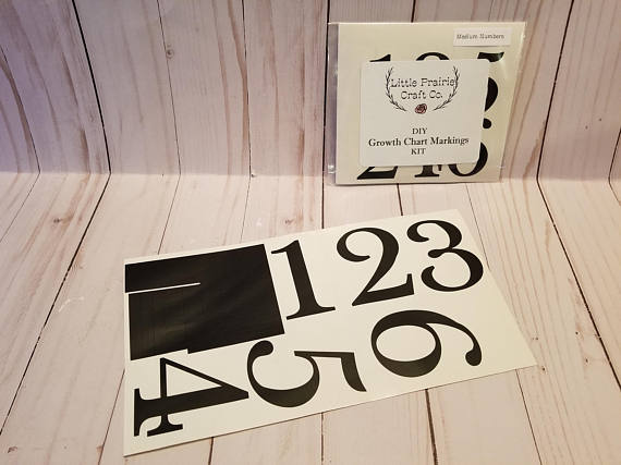 A set of black and white numbers on a wooden table, the Original DIY Growth Chart Vinyl Ruler Kit by Little Prairie Craft Co.