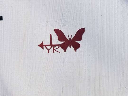 A Butterfly Height Marking Arrows is painted on the side of a wooden door by Little Prairie Craft Co.