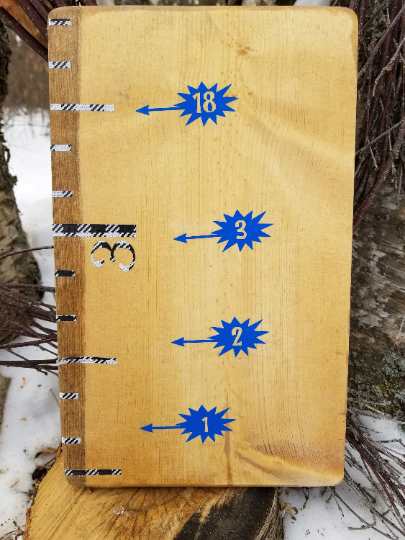 A wooden book with Little Prairie Craft Co.'s Comic Speech Bubble Height Marking Arrows on it.