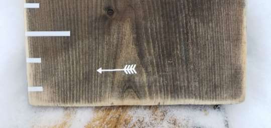 A wooden board with the Little Prairie Craft Co. Classic Blank Height Marking Arrows on it.