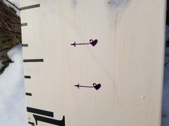 A Little Prairie Craft Co. wooden ruler with Lil Mini Hearts Height Marking Arrows on it.