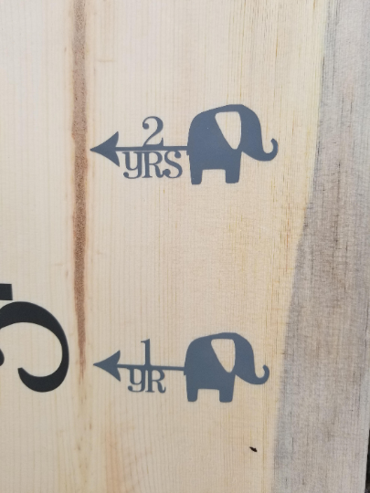 A wooden sign with Elephant Height Marking Arrows and Little Prairie Craft Co. brand on it.