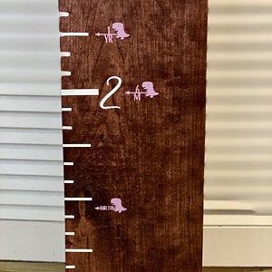 A Cutie Dino Height Marking Arrows growth chart with a pink and white design from Little Prairie Craft Co.