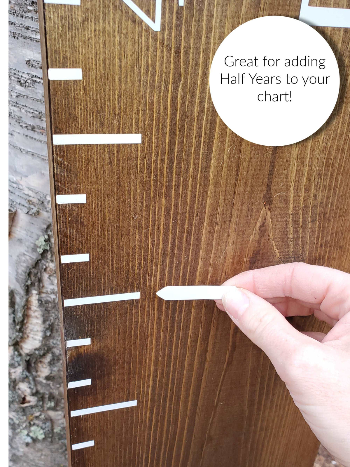 A hand is holding a Little Prairie Craft Co. Blank Write Yourself Height Marking Arrows wooden growth chart.