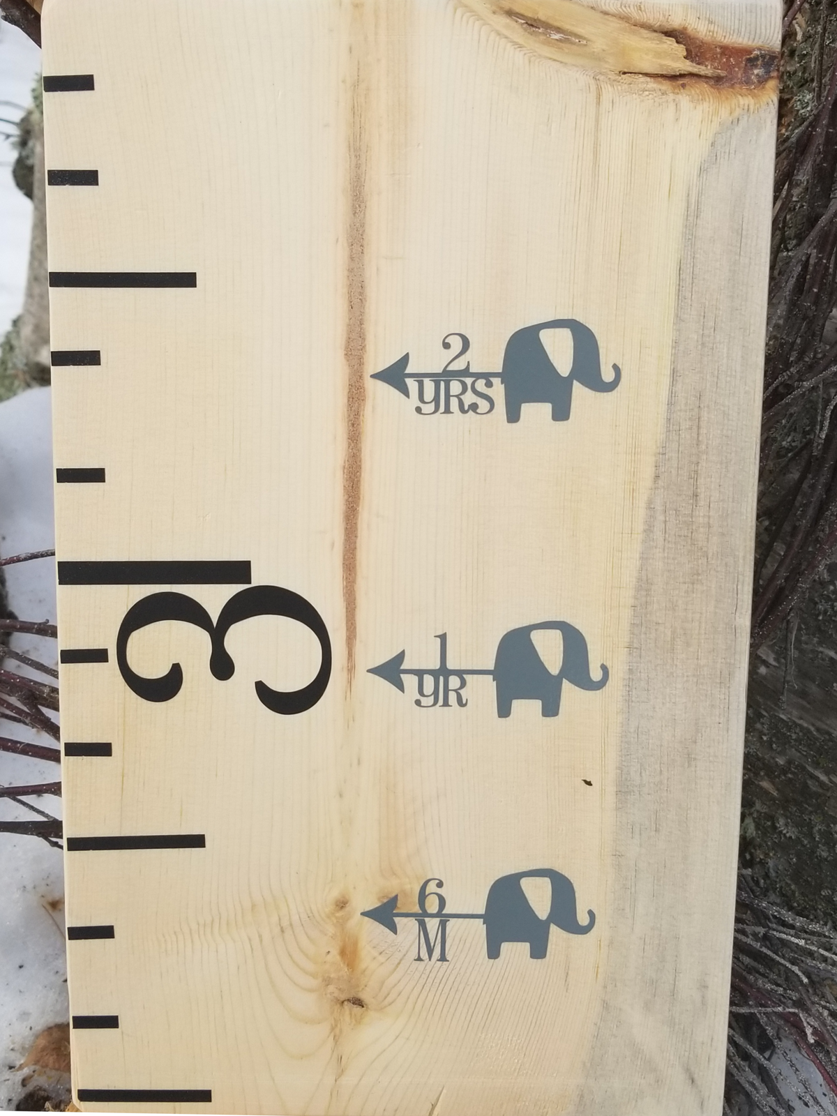 A wooden growth chart with Elephant Height Marking Arrows by Little Prairie Craft Co. on it.
