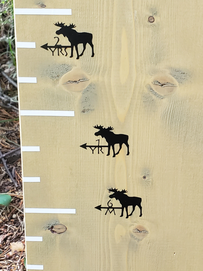 A wooden board with Moose Height Marking Arrows from Little Prairie Craft Co. on it.