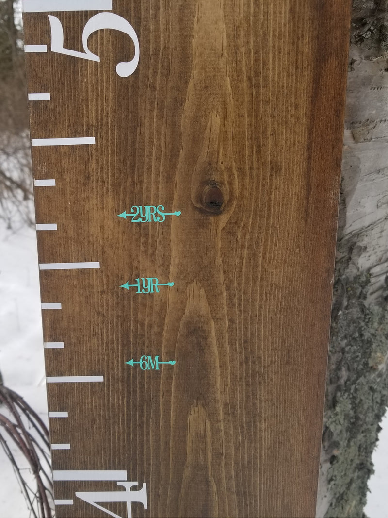 A wooden Pretty Little Heart Height Marking Arrows growth chart hanging on a tree by Little Prairie Craft Co.