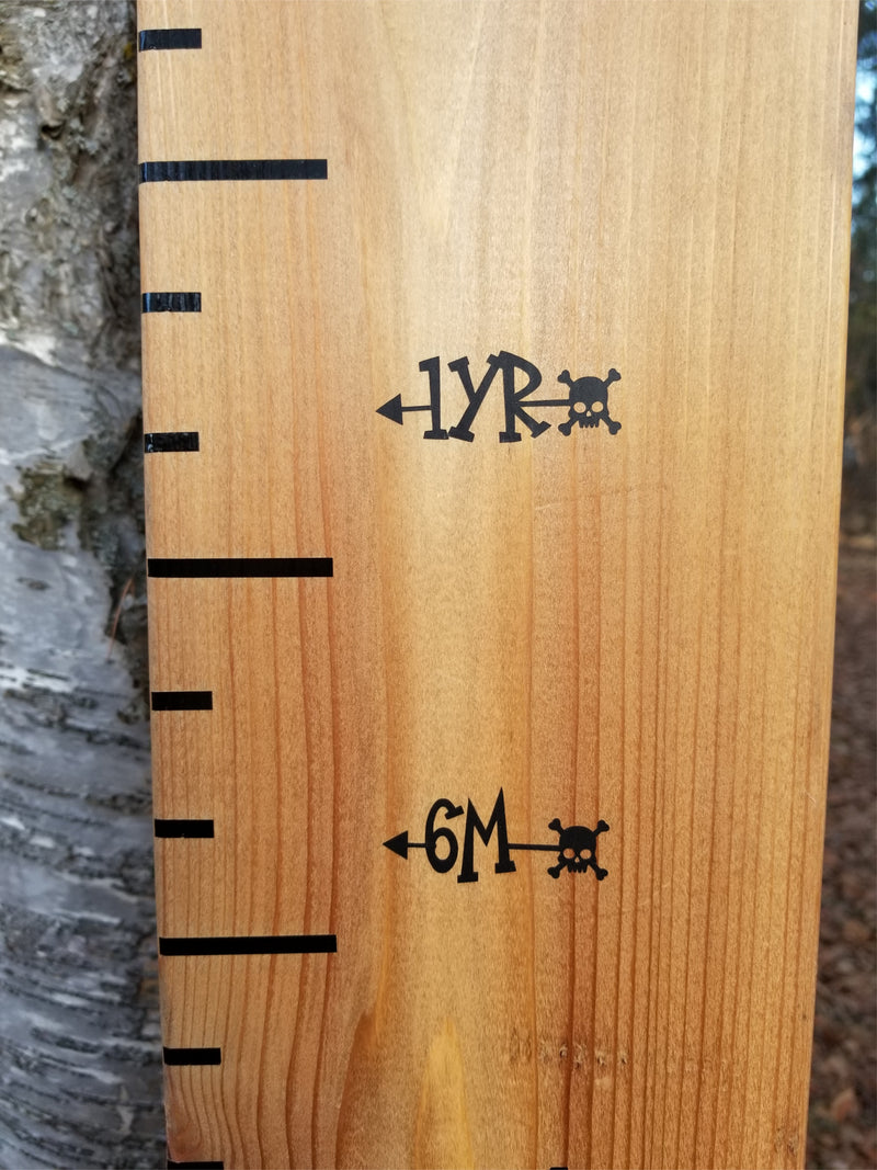 A Little Prairie Craft Co. wooden growth chart with writing on it featuring the Skull n' Bonez Height Marking Arrows.