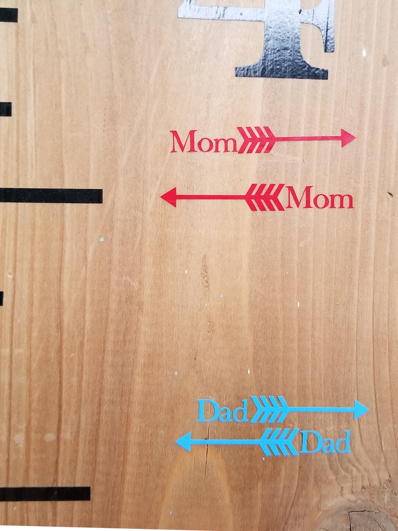 Arrows on a wooden board with the words mom and dad have been replaced with Skinny Classic Parent Height Markers by Little Prairie Craft Co.